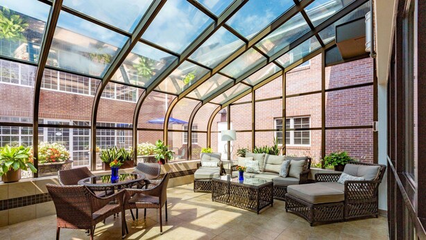 Una sala de estar con techo de vidrio, muebles de mimbre y plantas en macetas.