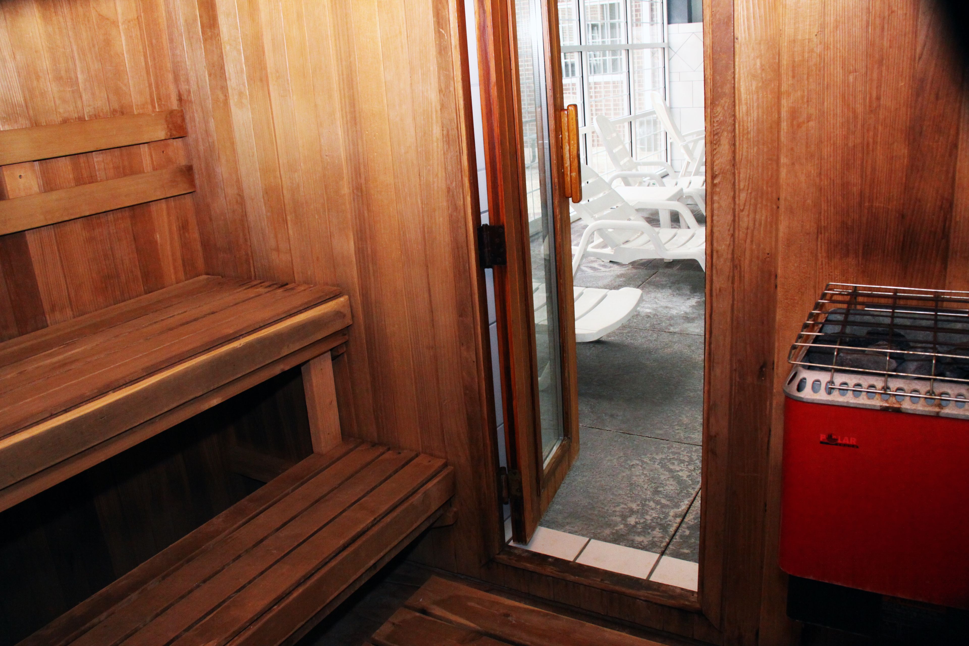 A sauna room with wooden benches and a red sauna heater.