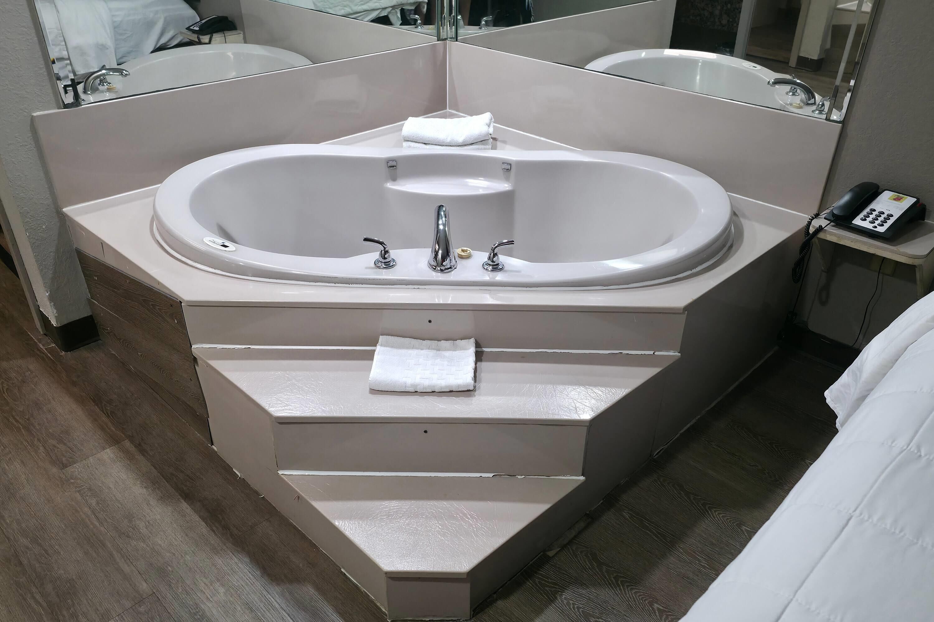 Un baño moderno con una bañera independiente, un tocador con espejo y un teléfono sobre una mesita.