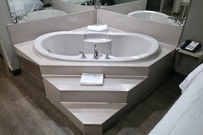 A modern bathroom with a freestanding bathtub, a vanity with a mirror, and a telephone on a small table.
