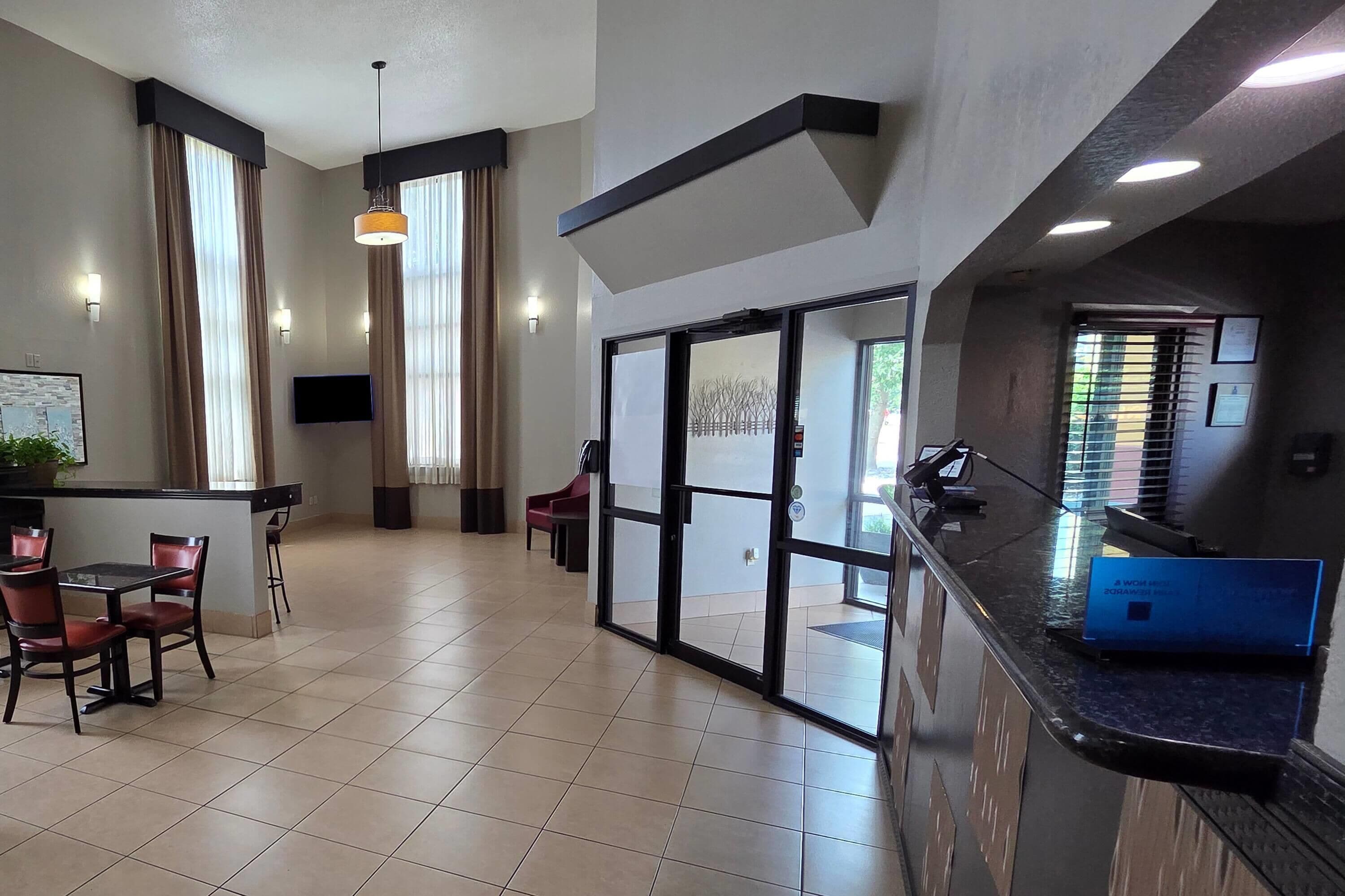 A hotel lobby with a reception desk, seating area, and large windows.