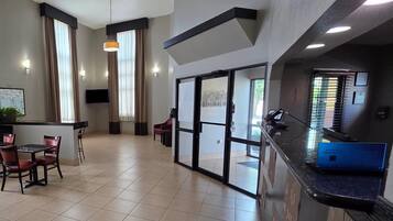 A hotel lobby with a reception desk, seating area, and large windows.