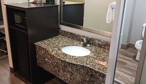 A bathroom with a granite countertop, a white sink, a mirror, and a toilet. - Super 8 by Wyndham Richland MS (Richland)