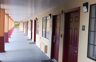 A row of hotel rooms with red doors and beige walls, numbered 101.
