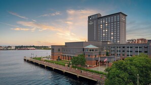 Ein Hotel mit moderner Architektur, das einen markanten Turm und eine Lage am Wasser aufweist.