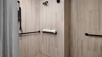 A shower area with a tiled wall, a towel rack, and a showerhead.