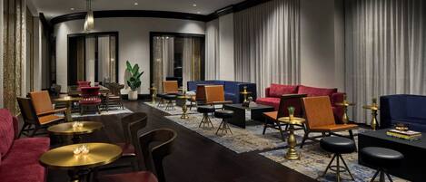 Un hall d’hôtel moderne offrant différents types de sièges, notamment des canapés, des fauteuils et un espace bar.
