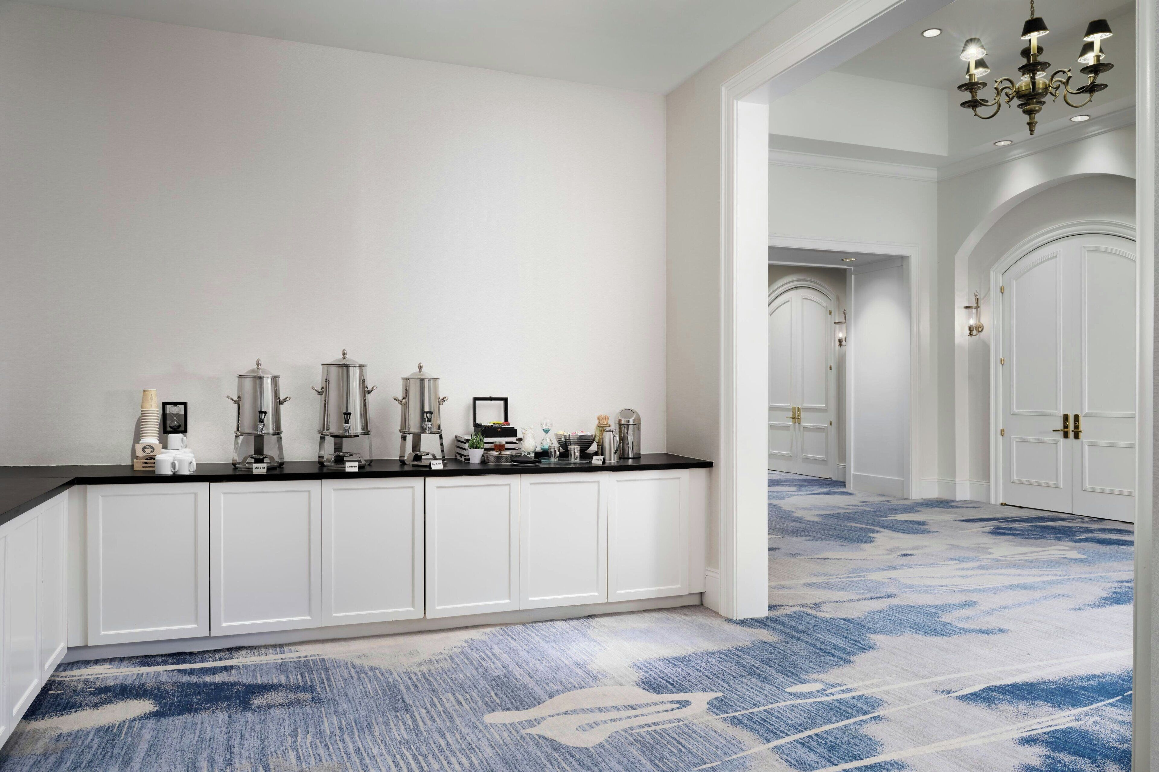 Une pièce spacieuse avec un grand meuble blanc, un comptoir noir et un tapis bleu à motifs.