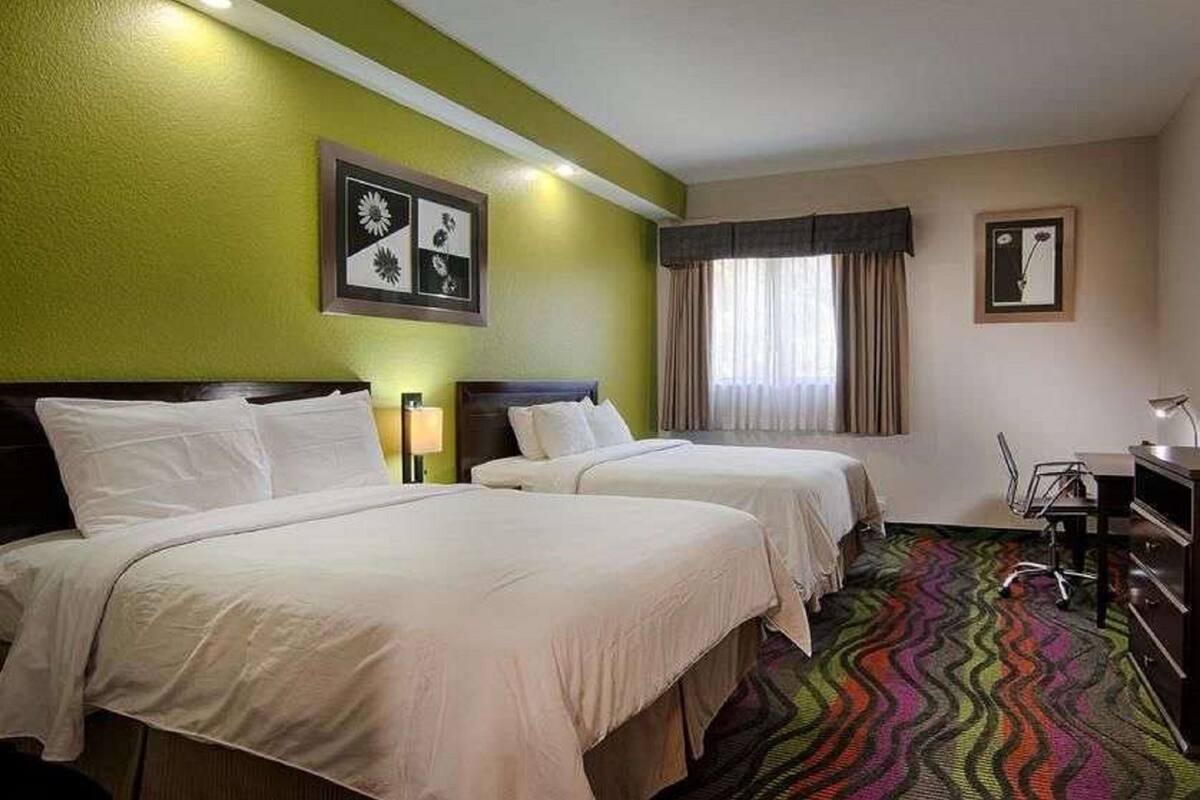 Ein Hotelzimmer mit zwei Betten, einem Schreibtisch und einem Stuhl.