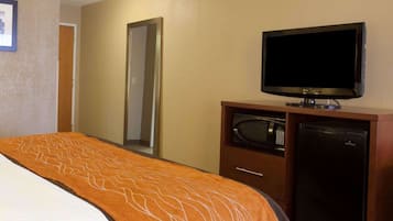 Una habitación de hotel con una cama, televisión, microondas y refrigerador.