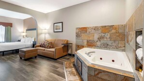 A modern hotel room with a large bed, a sofa, a small table, a desk, and a bathtub. - Best Western Plus Des Moines West Inn & Suites (Clive)