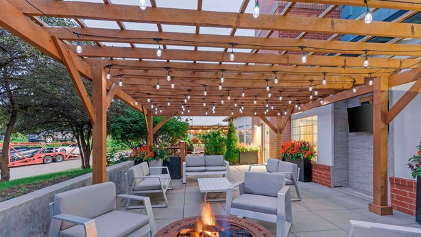 An outdoor patio with a fire pit, seating, and a pergola with string lights. - Best Western Plus Des Moines West Inn & Suites (Clive)