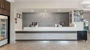 A reception area with a counter, two monitors, a refrigerator, and a tiled floor. - Best Western Plus Des Moines West Inn & Suites (Clive)