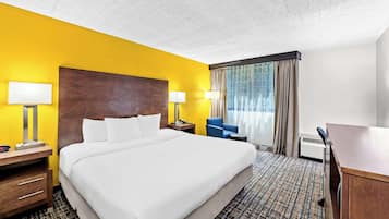 A hotel room with a large bed, two bedside tables with lamps, a desk, and a chair.