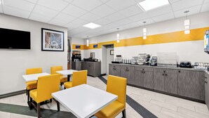 A modern restaurant with yellow chairs, white tables, and a kitchen area. - Best Western The Inn at Ramsey-Mahwah (Ramsey)