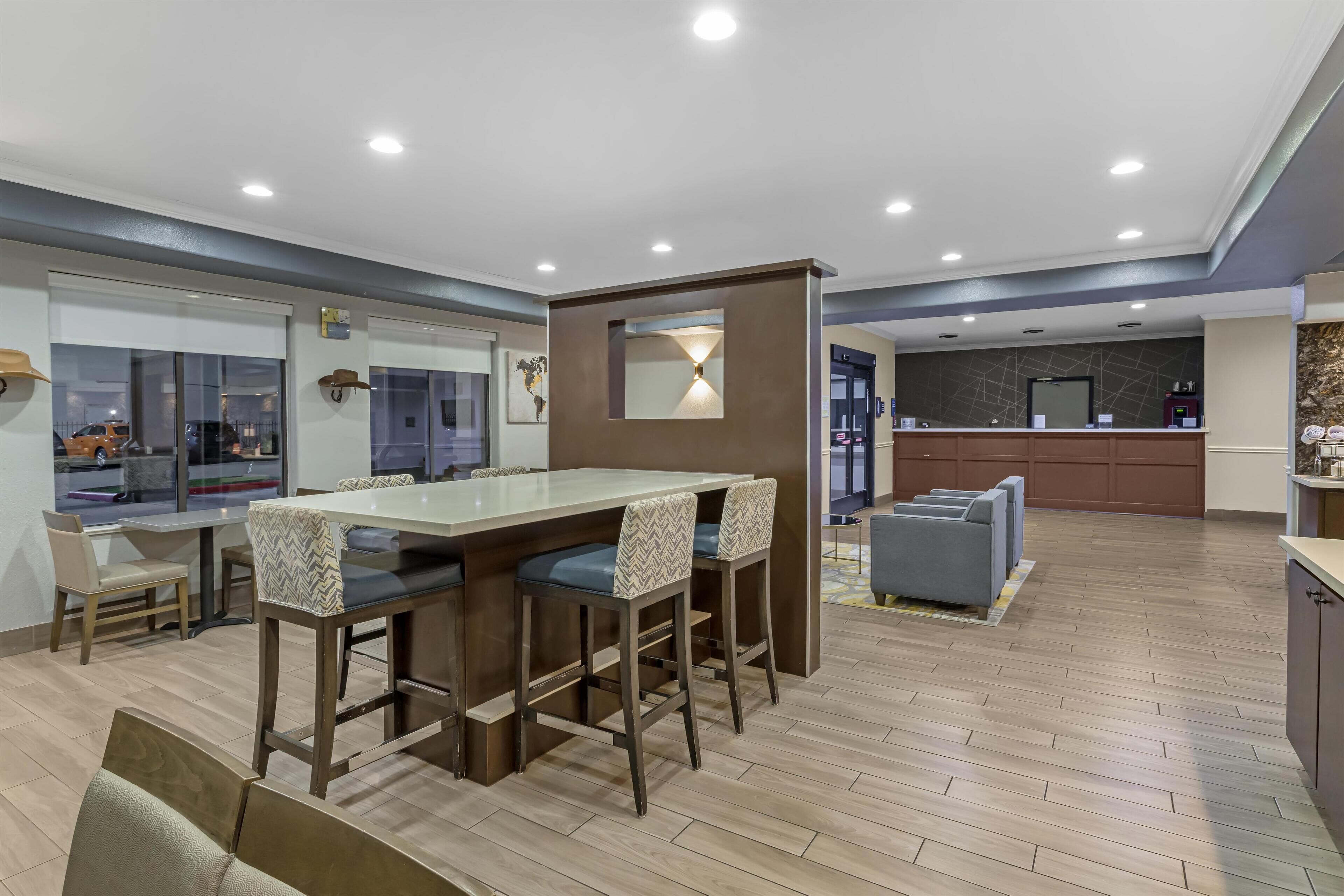 A modern kitchen with a central island, bar stools, and a seating area with sofas.
