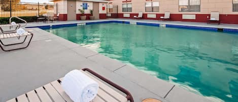 A pool area with lounge chairs and a towel rack.