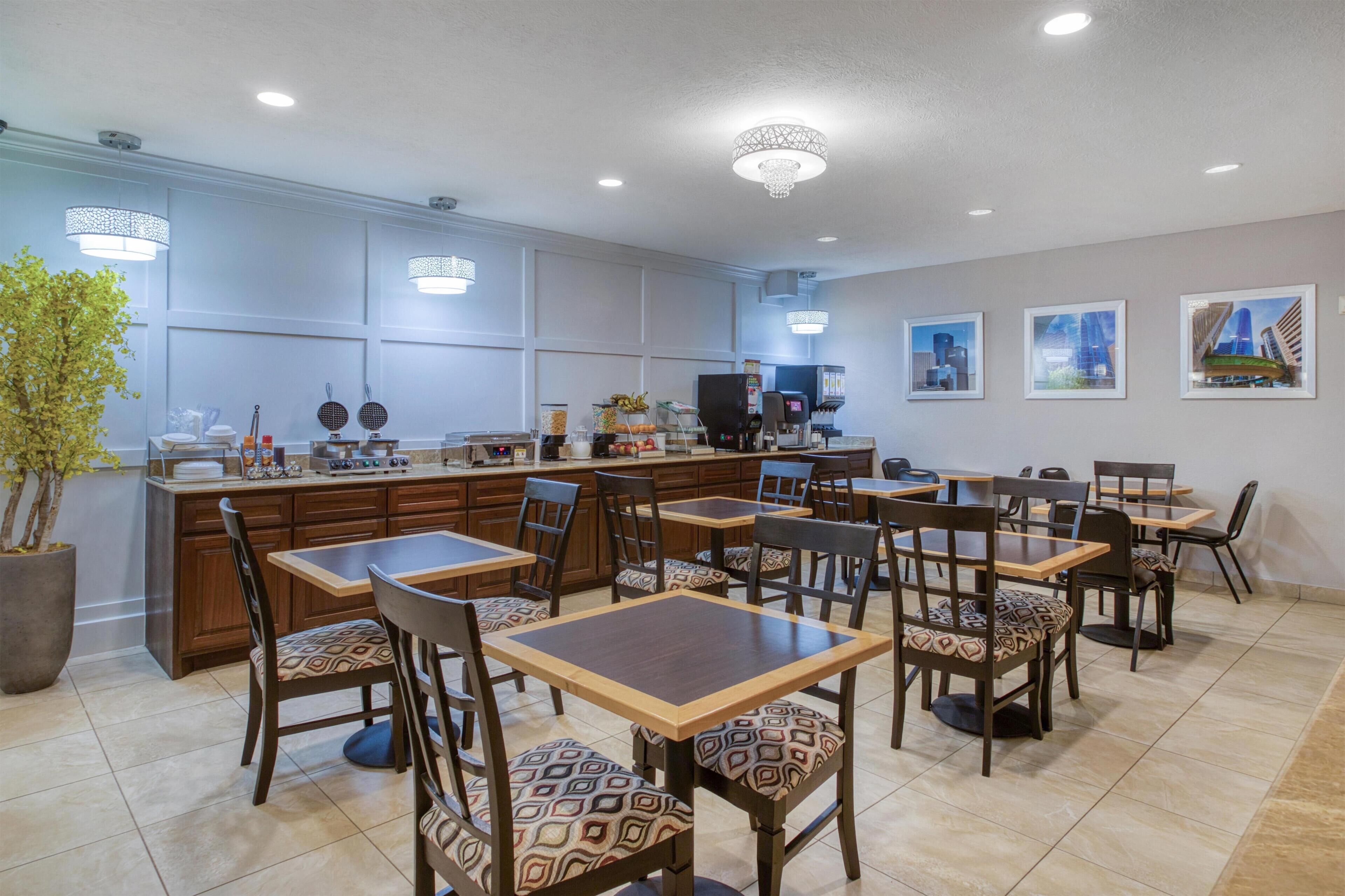 A restaurant with a bar area, multiple tables and chairs, and a large potted plant.