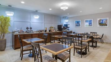 Un restaurante con barra, varias mesas y sillas, y una planta grande en maceta.