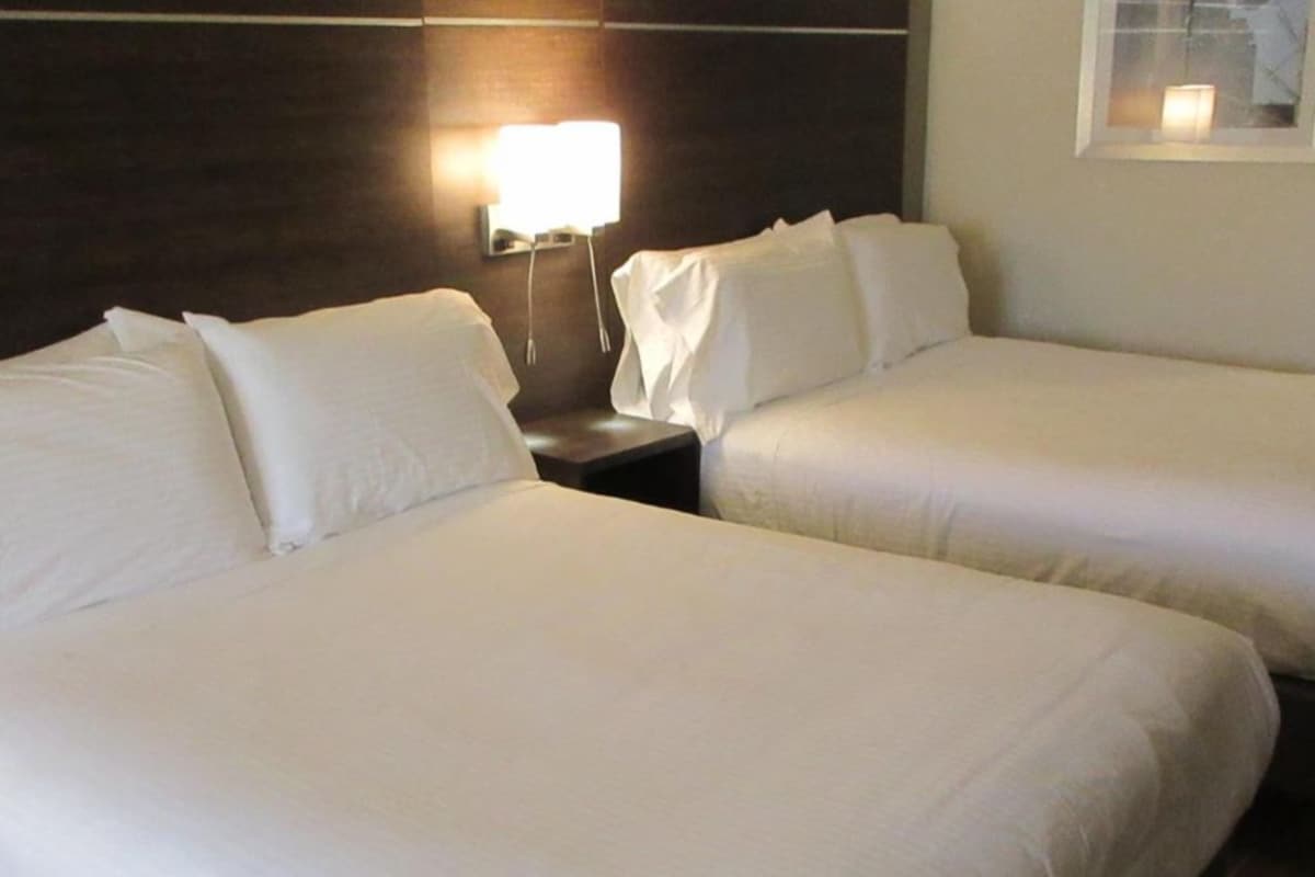 Two single beds with white linens, a nightstand with a lamp, and a framed picture on the wall.