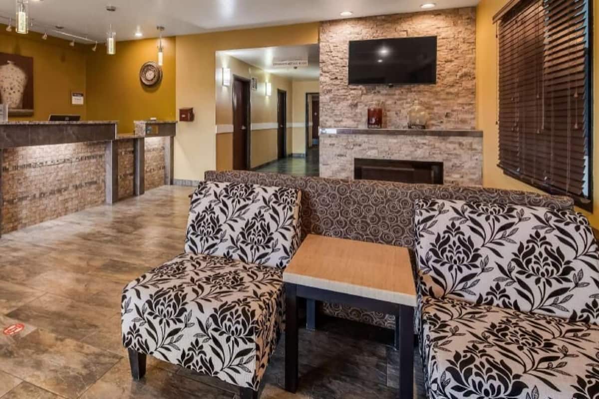 A reception area with a marble counter, patterned sofas, a small table, and a TV mounted on a stone wall.