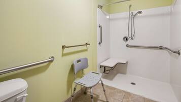 A bathroom with a wheelchair-accessible shower, grab bars, and a toilet.