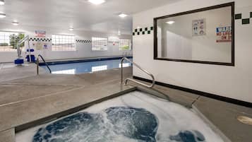 A swimming pool area with a hot tub, safety signs, and a lifeguard chair.