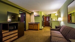 A hotel room with a kitchenette, a sofa, a TV, and a mirror. - Best Western Rama Inn (Ephrata)