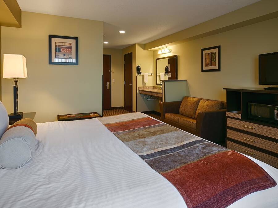 Una habitación de hotel con una cama grande, un escritorio, una silla, un televisor y un microondas.