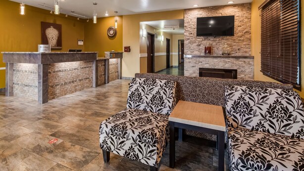 A reception area with a marble counter, patterned sofas, and a fireplace. - Best Western Rama Inn (Ephrata)