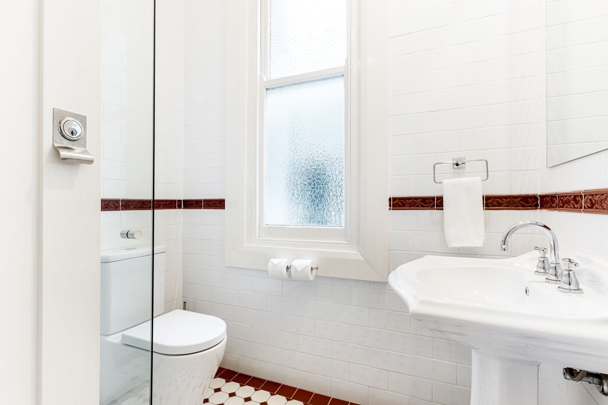 A bathroom with a toilet, sink, and window.