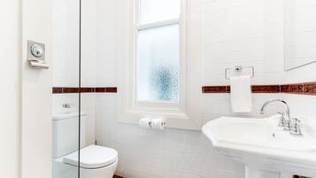 A bathroom with a toilet, sink, and window.