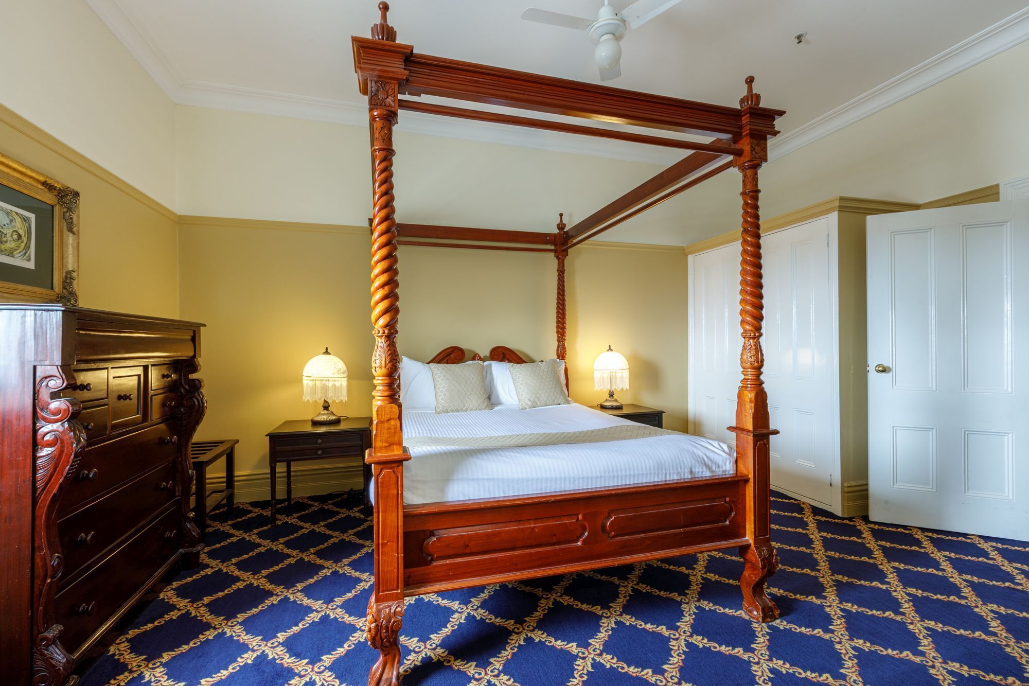Uma cama de dossel com estrutura de madeira e um tapete azul estampado.