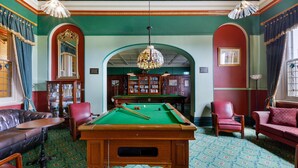 A billiards room with a pool table, leather seating, and a bookcase. - The Carrington Hotel (Katoomba)