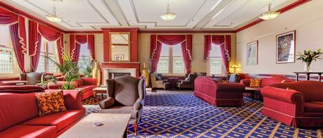 A spacious lobby with red sofas, a patterned carpet, and a large mirror.