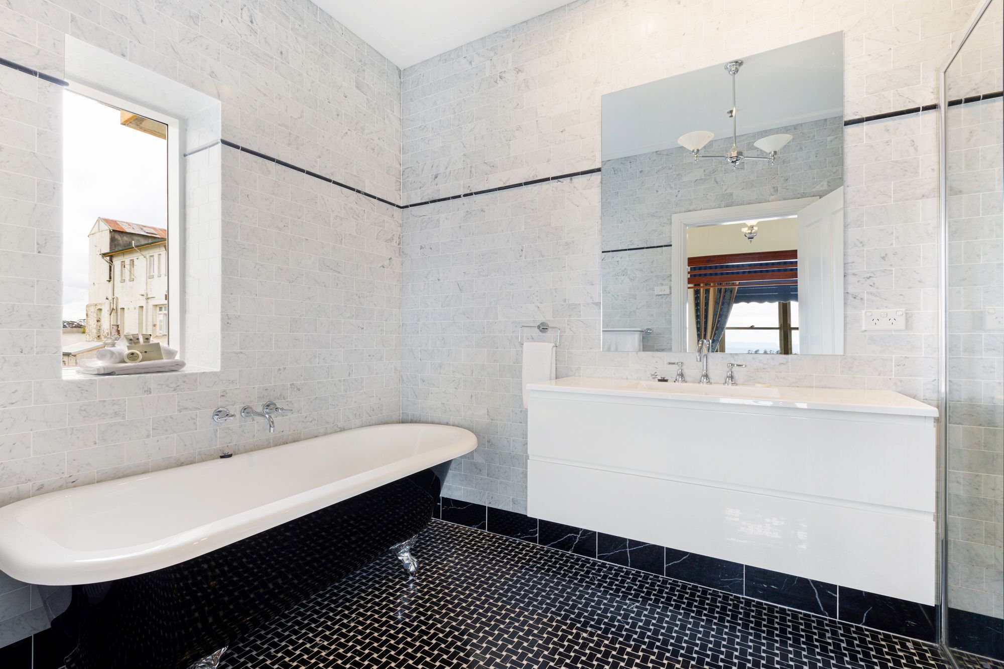 A bathroom with a freestanding bathtub, a vanity with a mirror, and a shower area.