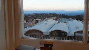 A view from a window overlooking a cityscape with buildings and distant mountains. - The Carrington Hotel (Katoomba)
