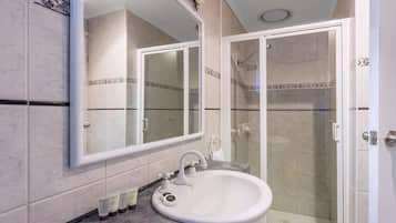 A bathroom with a sink, mirror, and shower.