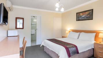 A hotel room with a bed, bedside lamps, a TV, a desk with a chair, and a framed picture on the wall.