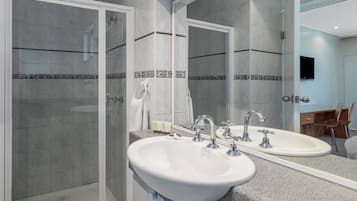 Un bagno moderno con cabina doccia, due lavandini e uno specchio grande.