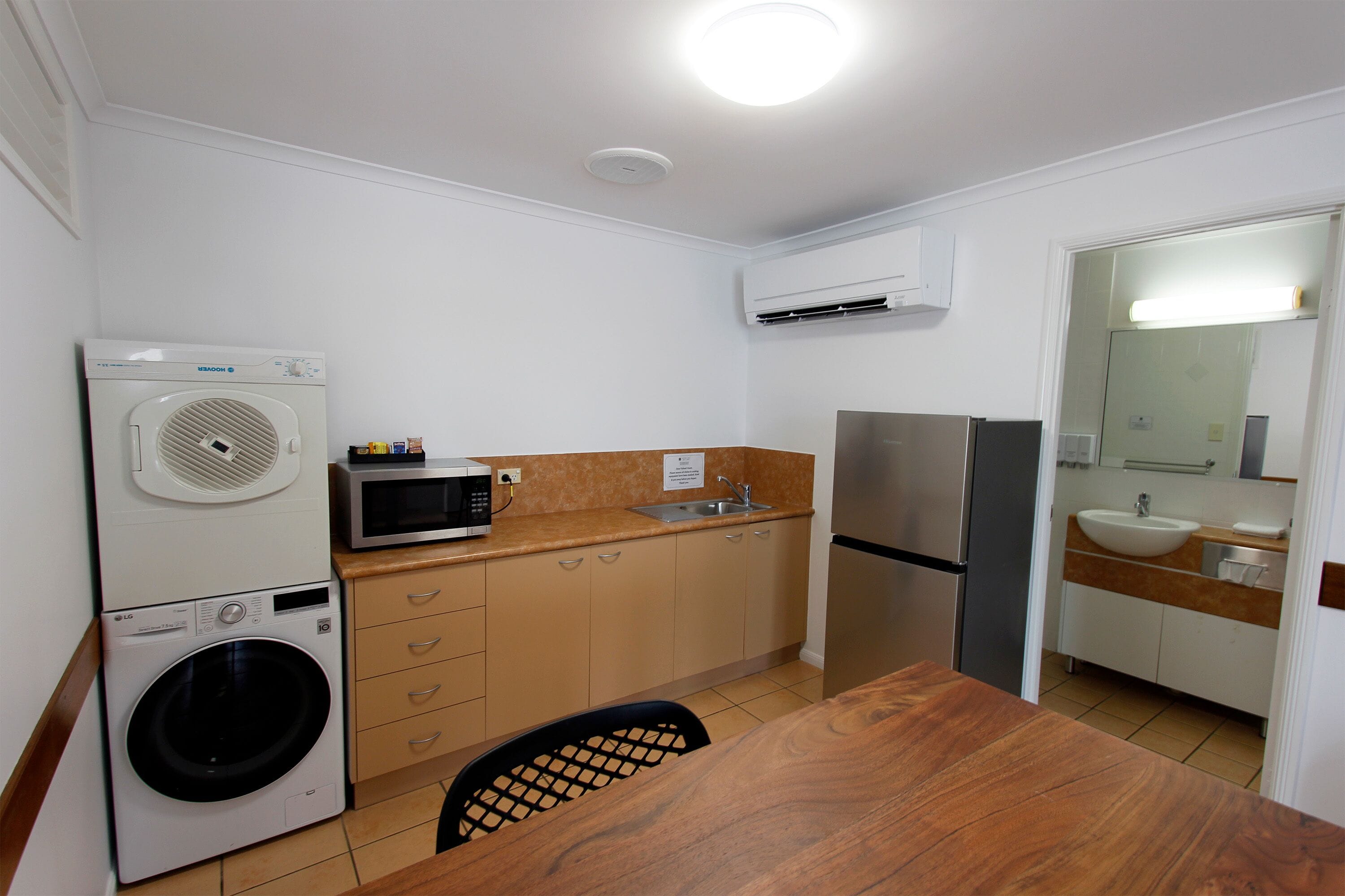 A compact kitchen with a washing machine, microwave, refrigerator, and sink.