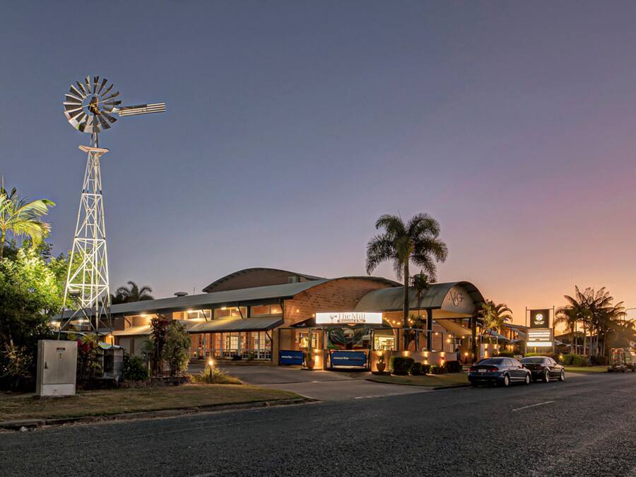 A hotel with a prominent windmill, a curved roof, and a sign that reads "The Mill."