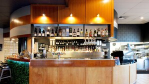 A bar area with wooden cabinets, shelves of bottles, and a coffee machine. - Windmill Motel and Events Centre (Mount Pleasant)