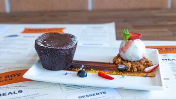 A dessert plate with a chocolate lava cake and a scoop of ice cream with fruit on top, garnished with a mint leaf.