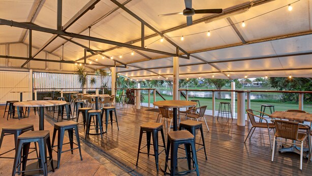 An outdoor dining area with tables and chairs, a ceiling fan, and string lights. - Windmill Motel and Events Centre (Mount Pleasant)