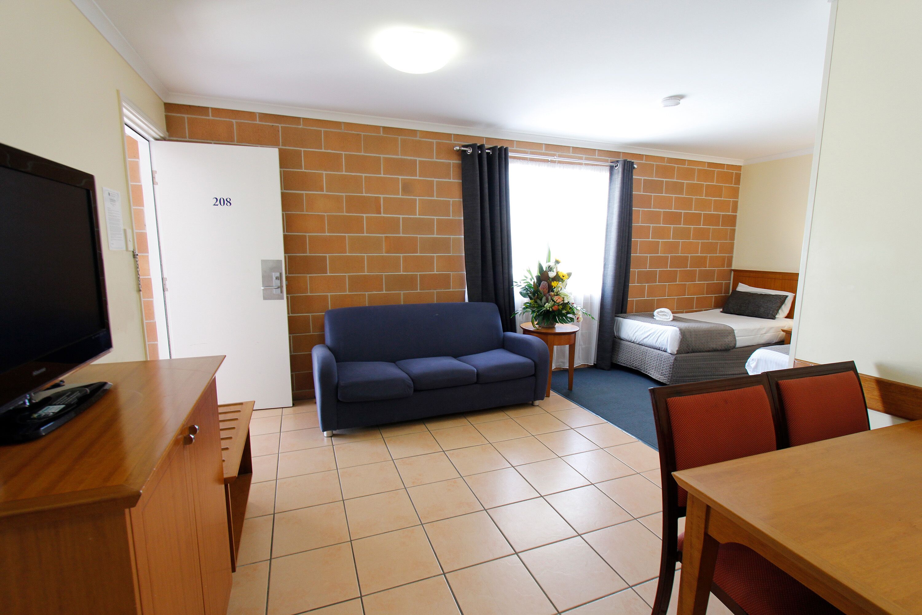 Una habitación con sofá, cama, televisión y mesa.