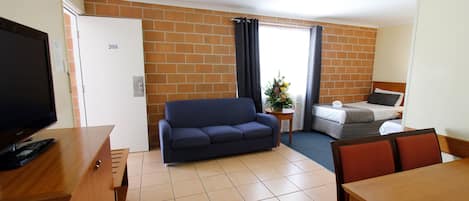 A room with a sofa, a bed, a TV, and a table.