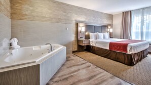 A modern hotel room with a large bathtub, a neatly made bed, and a large window with curtains. - Comfort Inn And Suites South (Calgary)