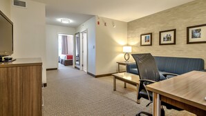 A hotel room with a wooden desk, a blue sofa, a lamp, and framed pictures on the wall. - Comfort Inn And Suites South (Calgary)