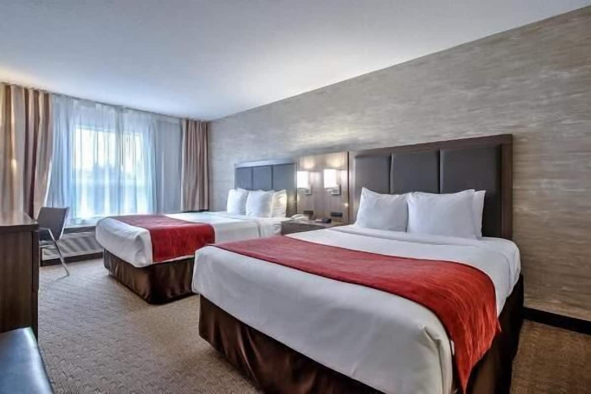 A hotel room with two beds, a desk, and a chair.